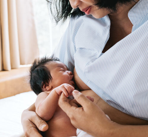 Mother breastfeeding newborn baby in comfortable setting.