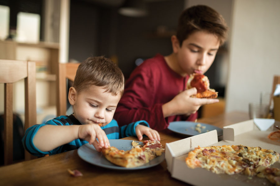 Children enjoying pizza at a kitchen table.