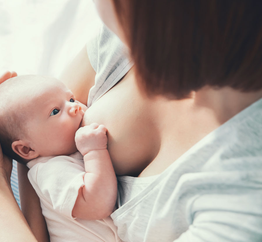 Baby breastfeeding in mother's arms, looking content.