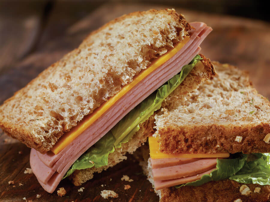 Whole grain sandwich with lettuce, ham, and cheese.