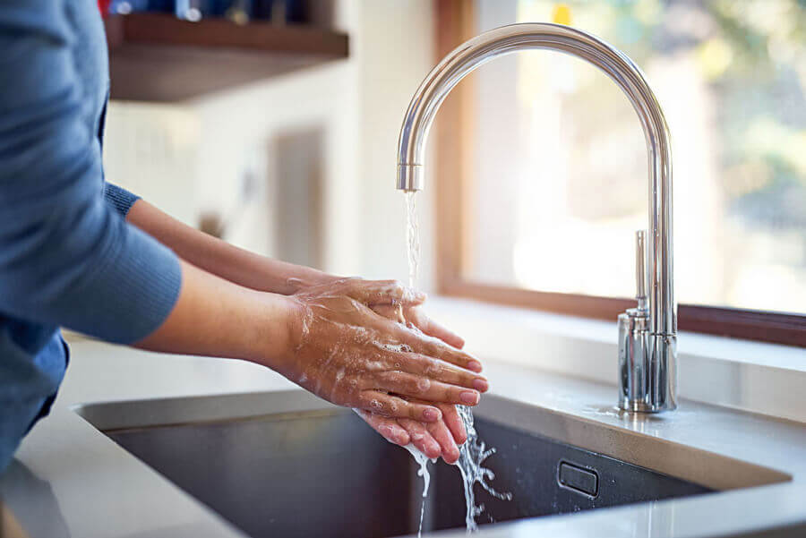 Hands being washed under running water in sink.