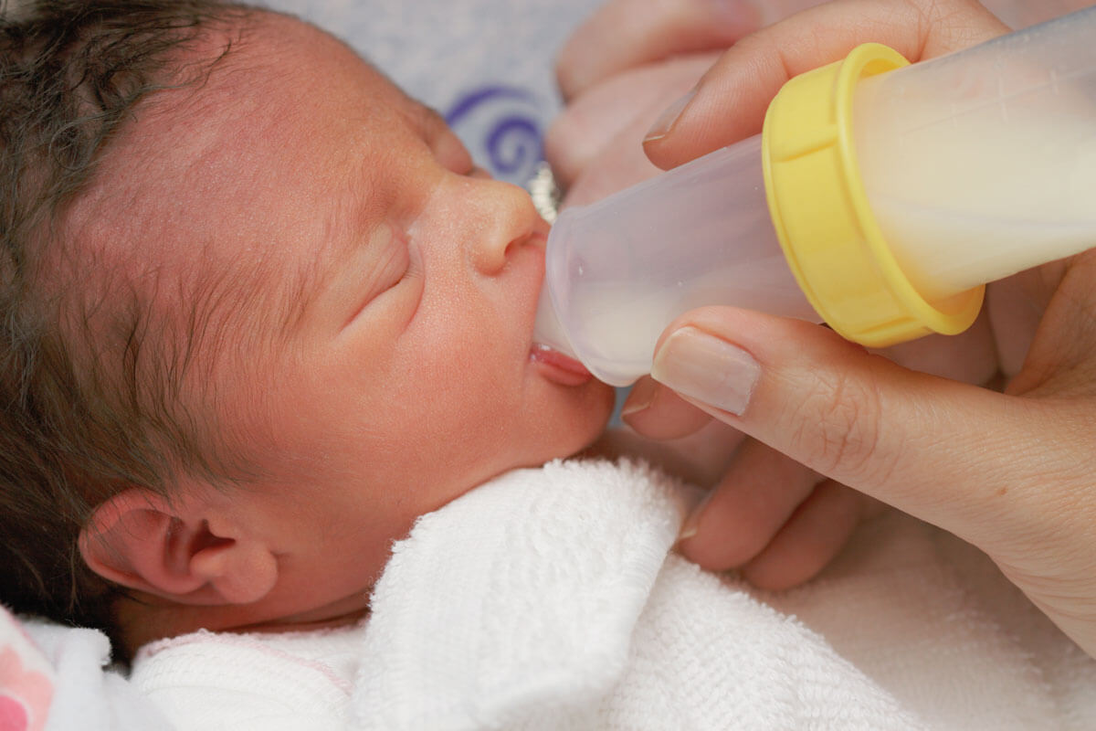 Newborn drinking from bottle, close-up.