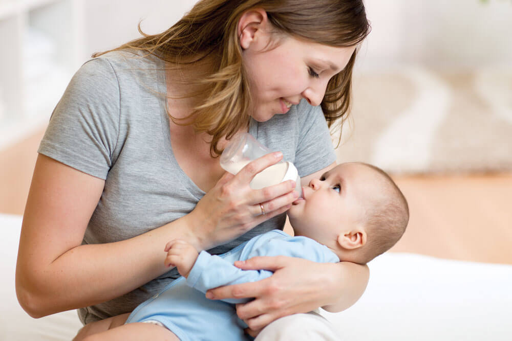 Mother feeding baby with a bottle, holding gently.