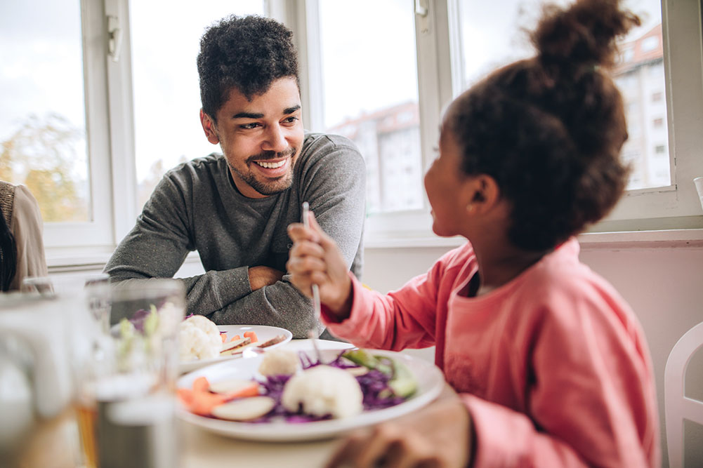 Father and daughter enjoying a meal together, smiling.