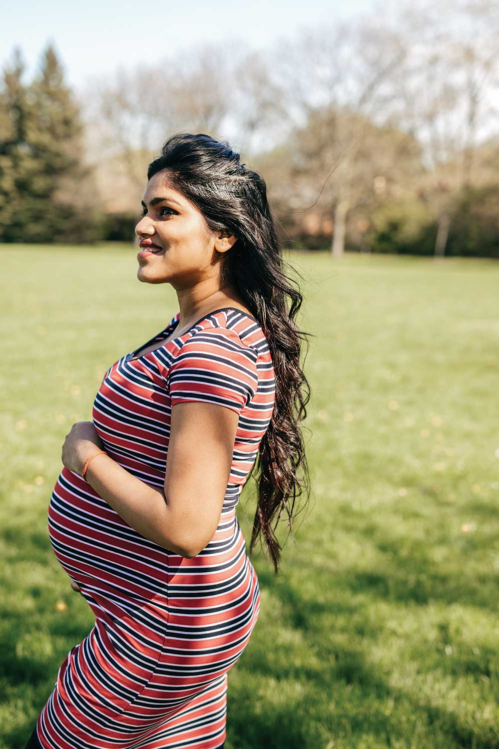 Pregnant woman smiling in a sunny park.