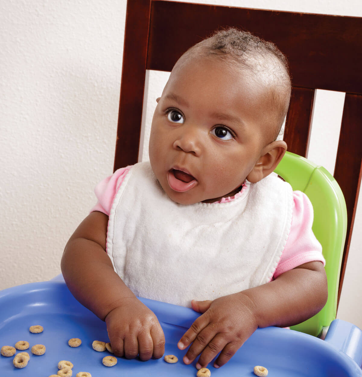 Baby eating cereal in high chair.