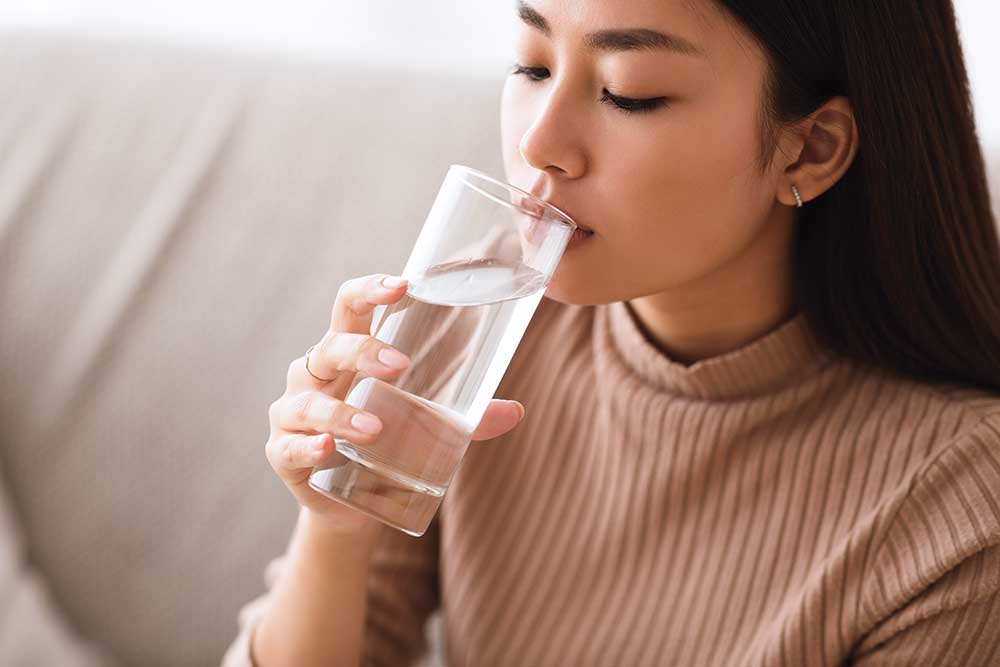 Woman drinking water from a clear glass.