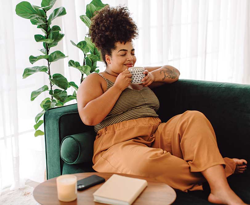 Woman relaxing on sofa with cup of tea.