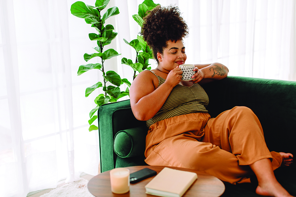 Woman sitting on a couch drinking coffee and relaxing at home