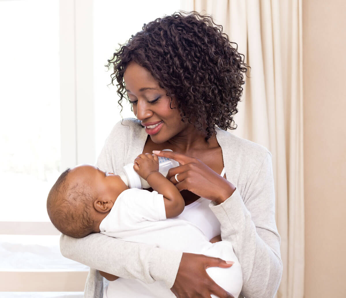 Mother smiling while bottle-feeding her baby.