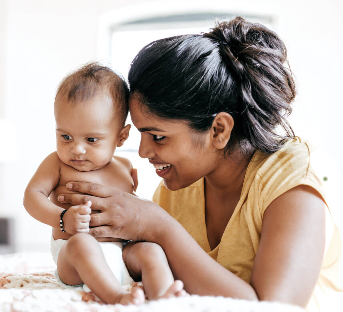 Smiling woman gently holding a curious baby.