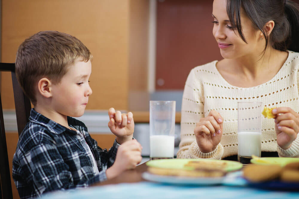 Child and woman enjoying snacks and milk together.