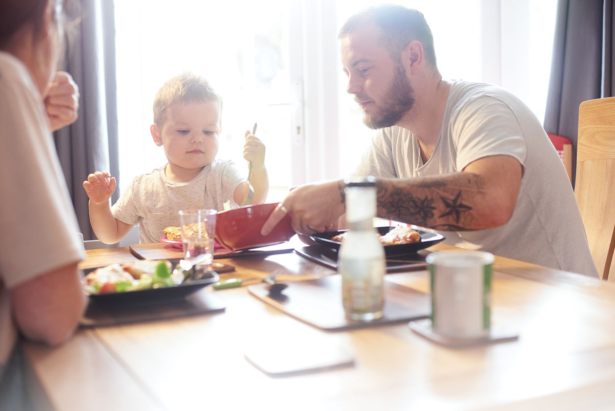 Family eating lunch together at sunlit table.