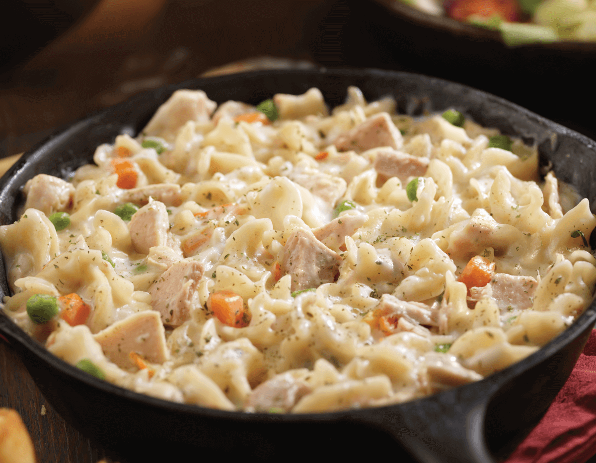 Creamy chicken noodle casserole in a black skillet.