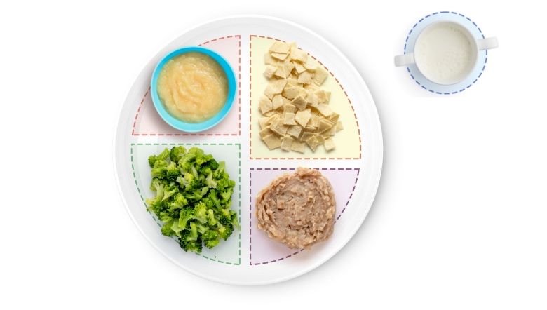 Divided plate with broccoli, applesauce, crackers, oatmeal. Cup nearby.