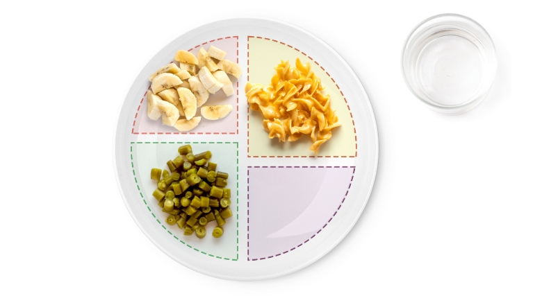 Divided plate with chicken, noodles, beans, and water.