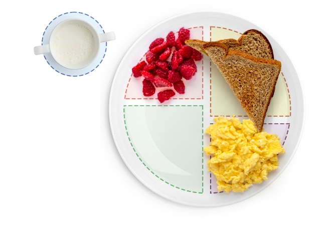 Divided plate with toast, scrambled eggs, strawberries, and milk.