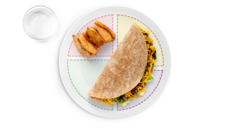 Whole wheat taco with potato wedges and water.