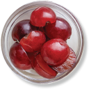 Bowl of fresh, halved red plums.