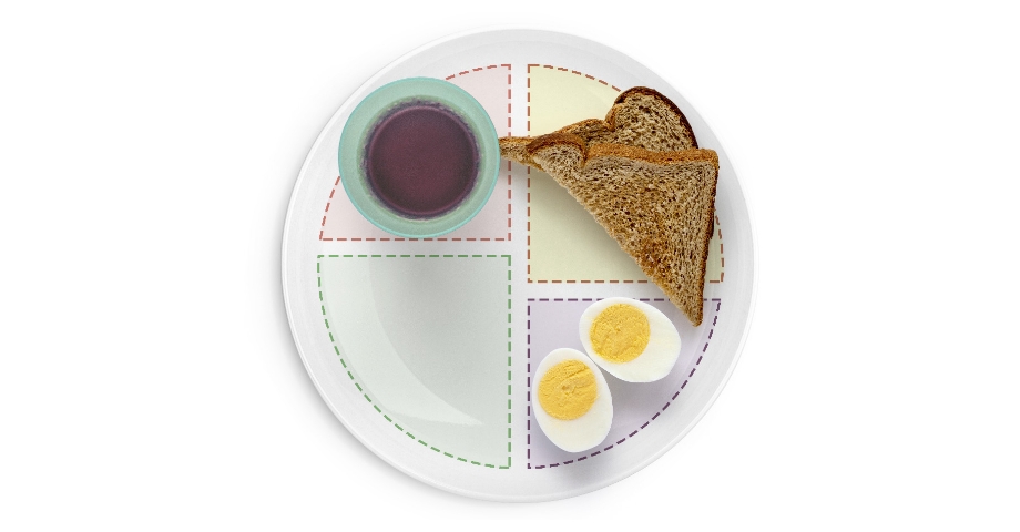 Toast, boiled eggs, and juice on divided plate.