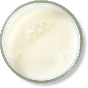 Glass of milk with bubbles on surface.