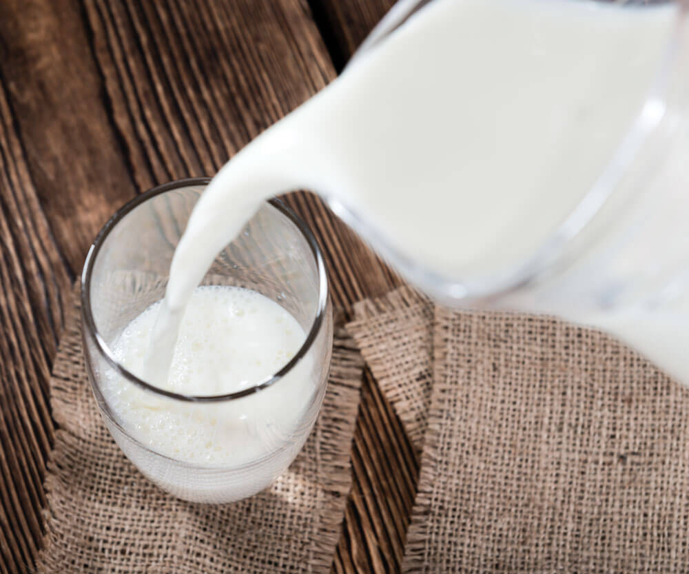 Pouring milk into a glass on burlap mat.