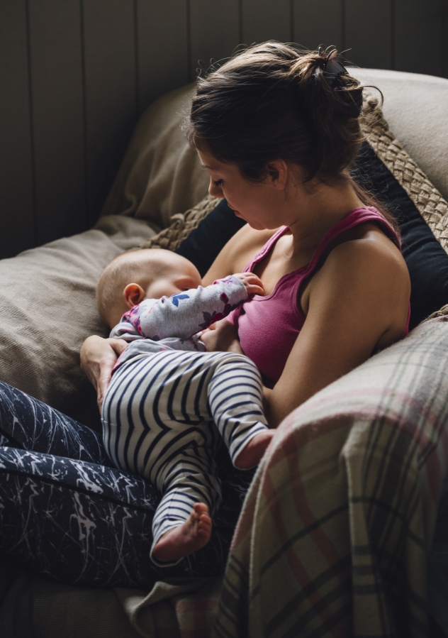 Mother breastfeeding her baby on a cozy couch.