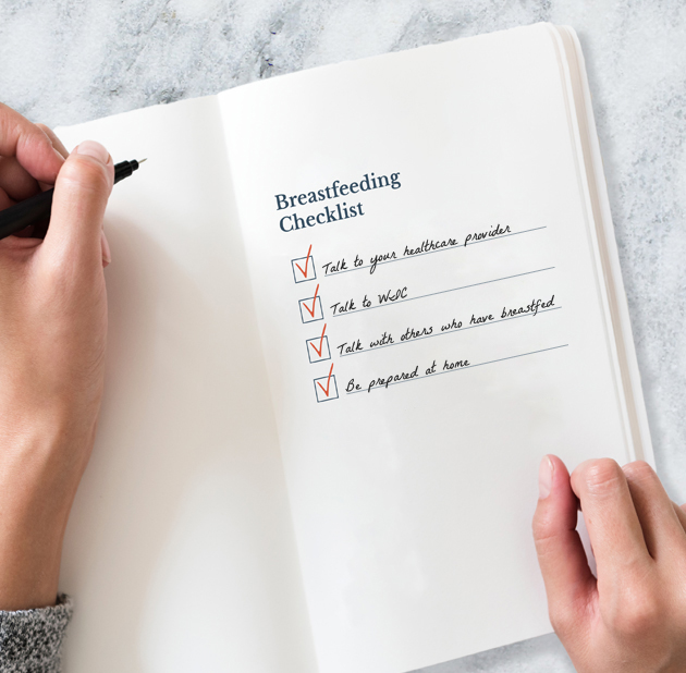 Hands writing breastfeeding checklist in notebook.