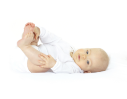 Baby lying on back, holding feet, smiling gently.