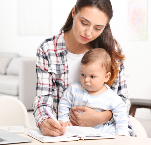 Parent studying while holding attentive baby.