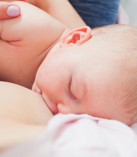 Baby breastfeeding in mother's arms, peacefully resting.