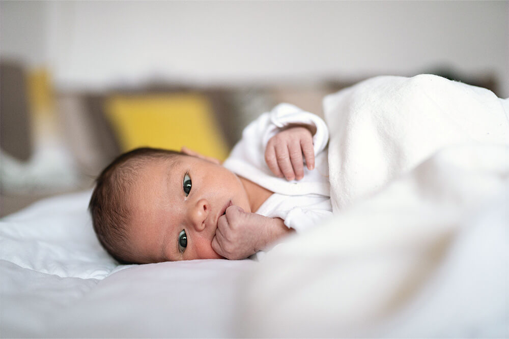 Baby lying on bed, gazing with curious eyes.