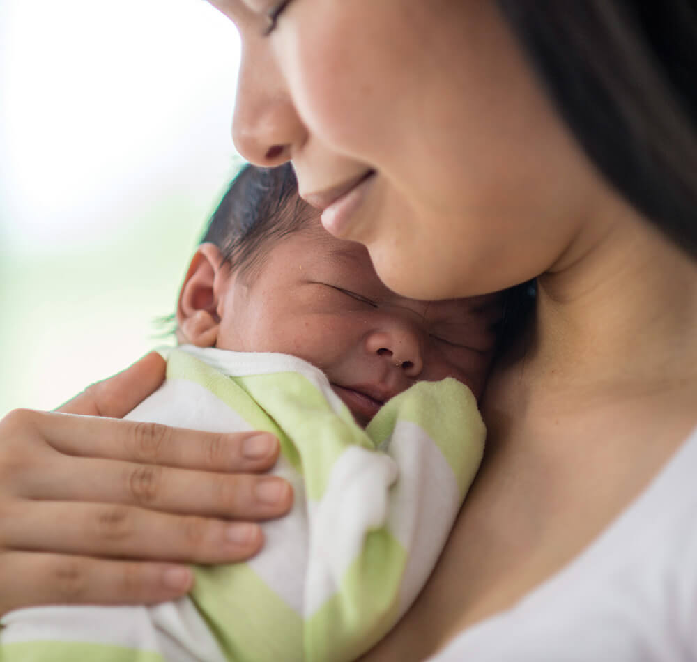 Mother lovingly holds sleeping baby close.