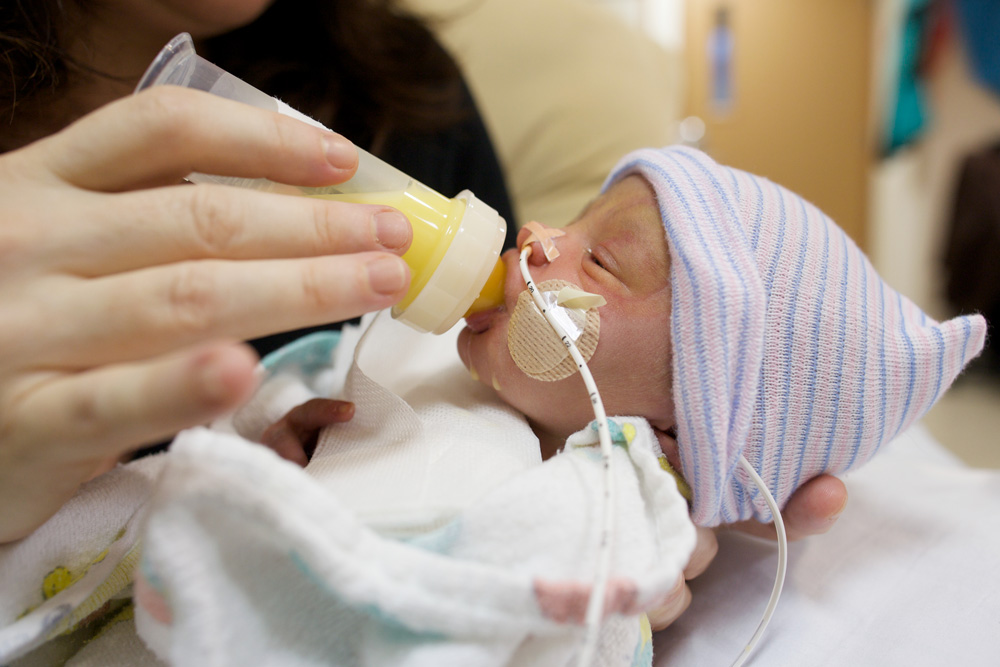 Premature baby being bottle-fed in hospital nursery.