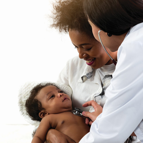 Doctor examining baby with stethoscope as mother smiles.