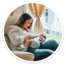 Mother breastfeeding baby in cozy, sunlit room.