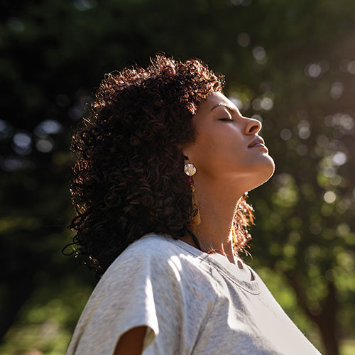 Woman basking in sunlight with eyes closed.