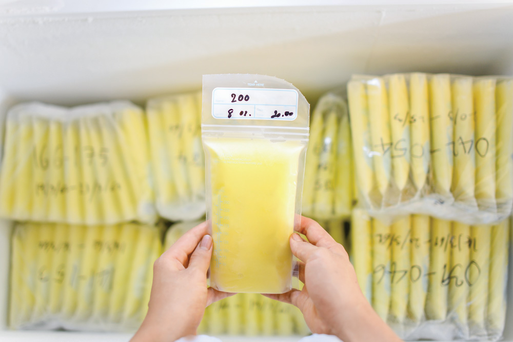 Hands holding frozen milk storage bag in freezer.