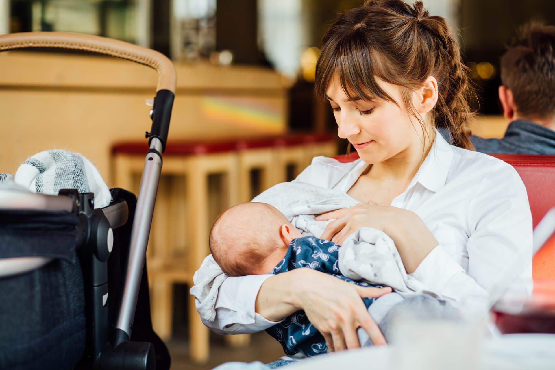 Mother breastfeeding baby in a cozy cafe