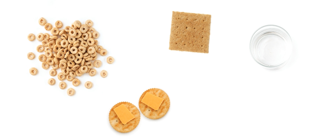 Crackers, cheese, cereal, graham cracker, and water displayed.