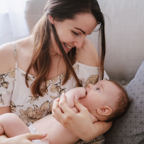 Mother breastfeeding her baby while smiling tenderly.