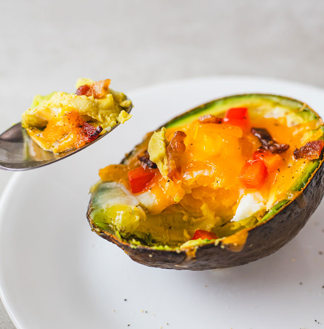 Avocado half baked with egg, cheese, and vegetables.