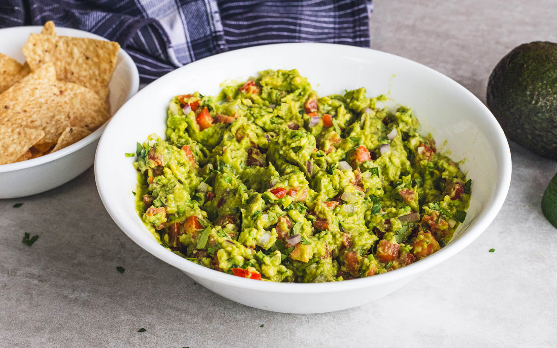 Guacamole in a bowl with tortilla chips nearby.