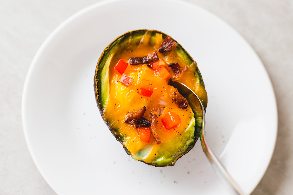 Baked avocado with egg, topped with peppers.