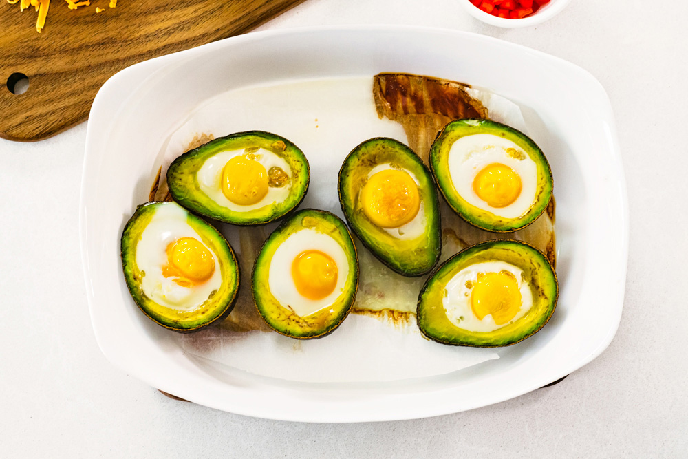 Baked avocados with eggs in a white dish.
