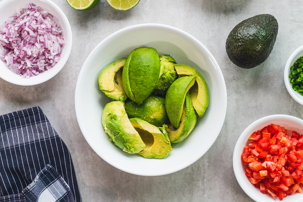 Avocado slices surrounded by diced vegetables ingredients.