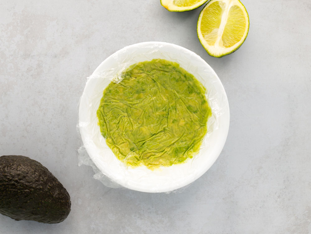 Bowl of guacamole covered in plastic wrap.