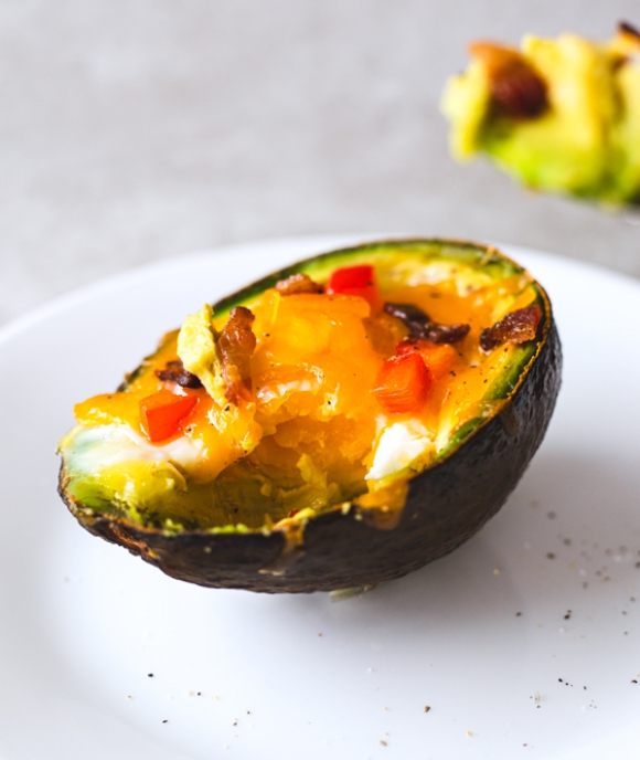 Avocado half filled with melted cheese and peppers.