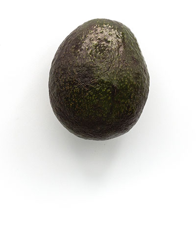 Whole avocado on plain white background.