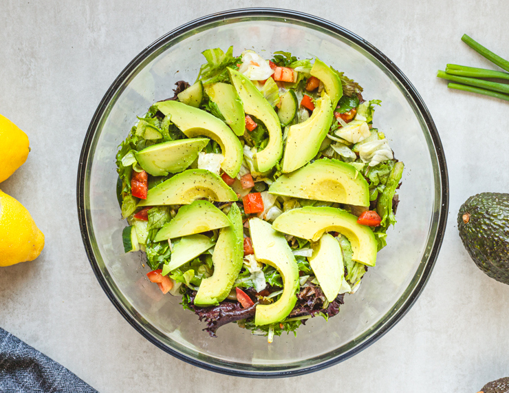 Fresh avocado salad with mixed greens in bowl.